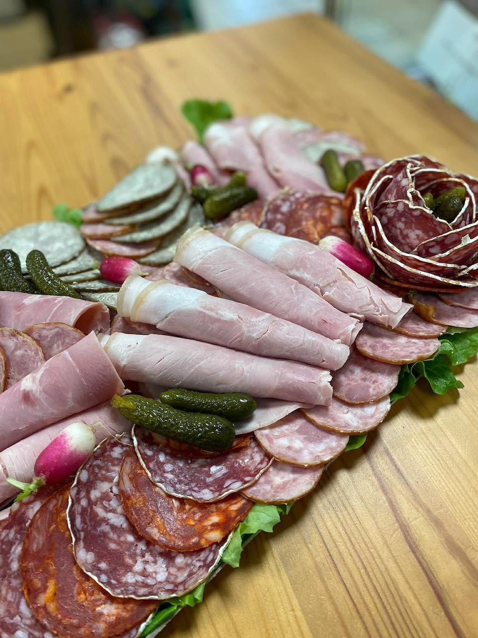Au Marché de l'Oust fait un gros plan sur charcuterie (jambon, rosette en fleur, andouille, cornichons, radis, salade, chorizo, etc)