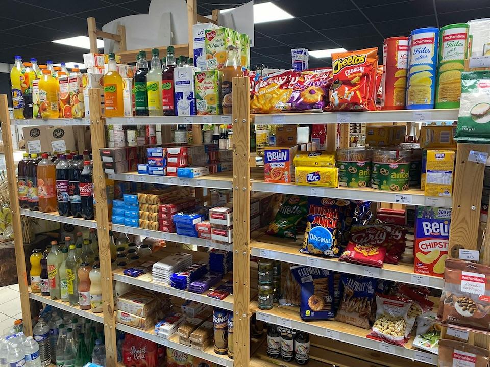 Rayon des produits plaisirs (sodas, gateaux apéritifs, tablettes de chocolat, etc) dans le magasin Au Marché de l'Oust