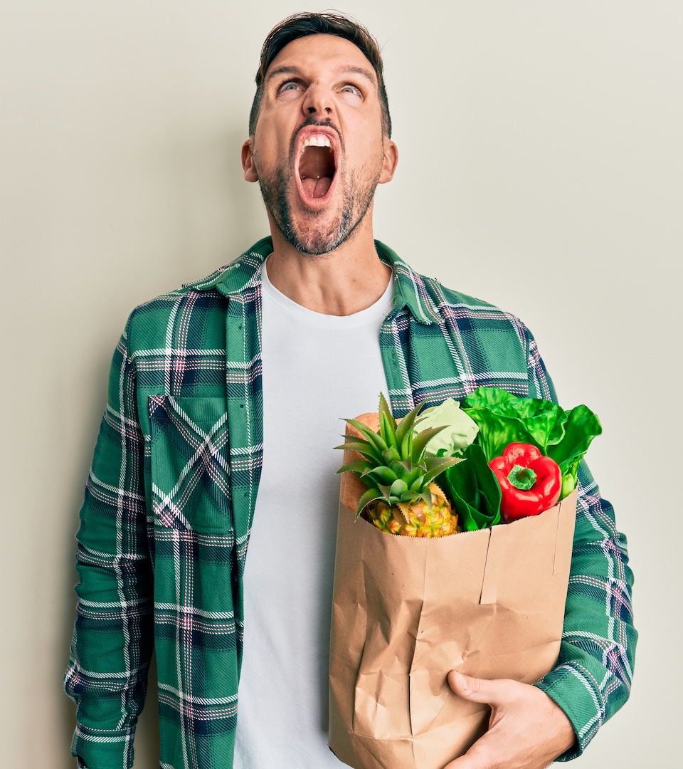 Homme avec une chemise à carreaux verts tenant un sac dans les courses qui hurle