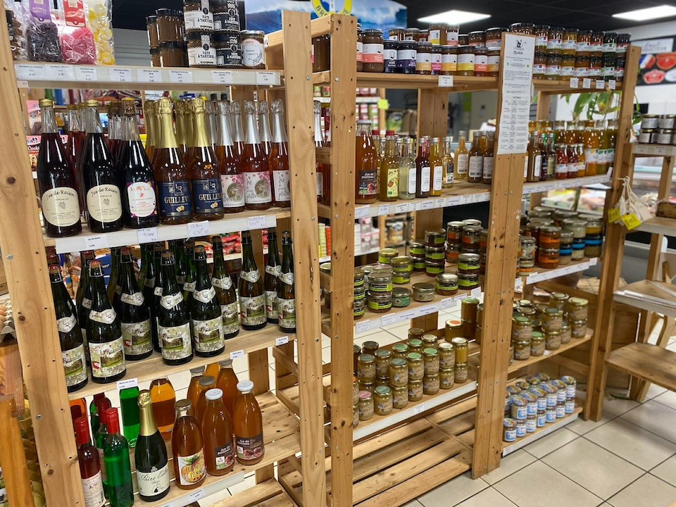 Étagères en bois du magasin Au Marché de l'Oust sur lesquelles on retrouve des bouteilles de vins et bières